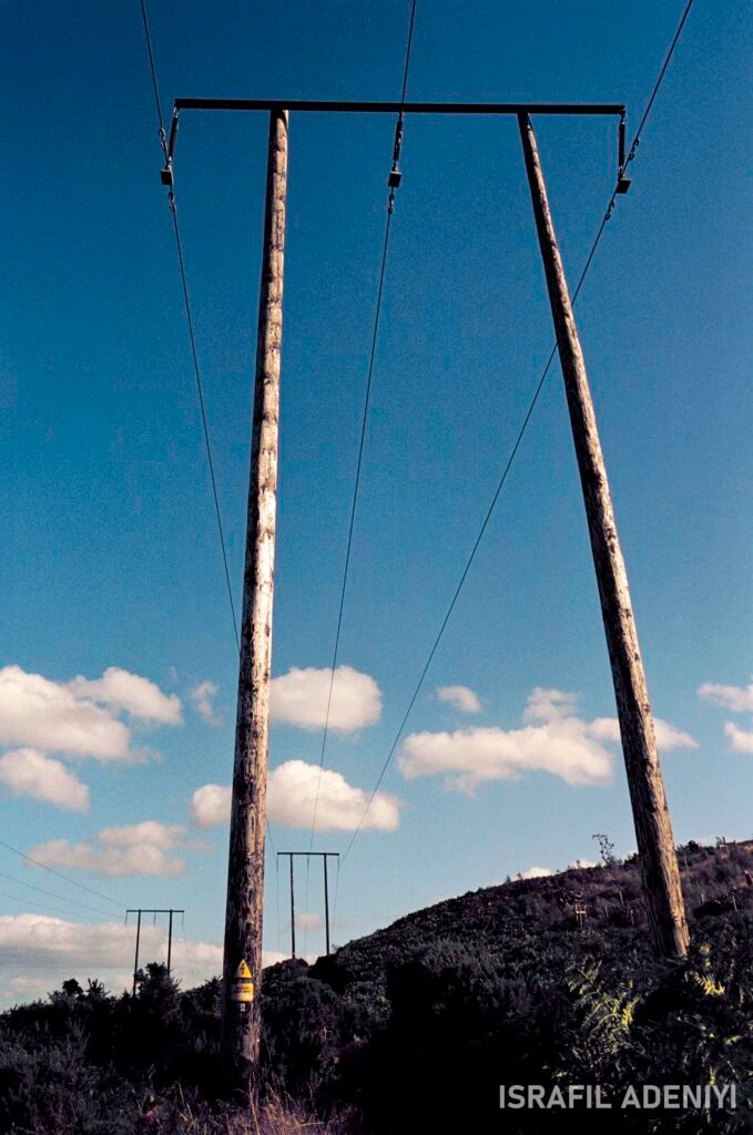 Powerlines on a hillside on a minimally cloudy day.