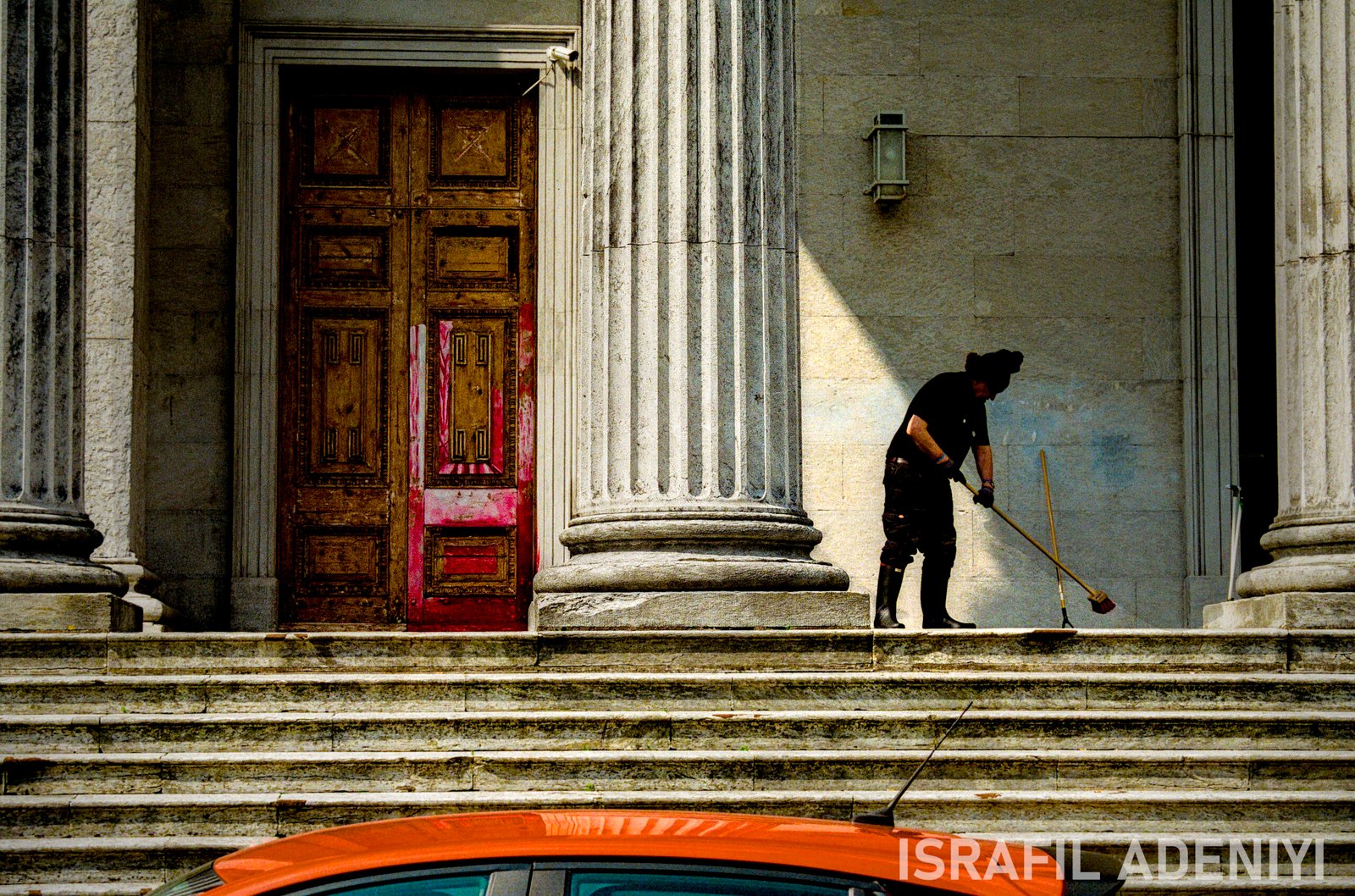 A person sweeping at the top of the steps of an official building.